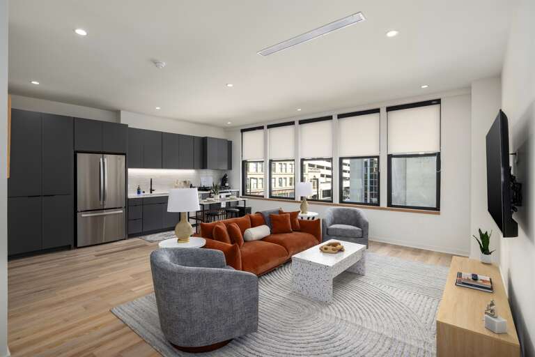 Sophisticated comfort—this open-concept living space blends the modern kitchen and cozy living room, bathed in natural light from expansive windows overlooking the city.