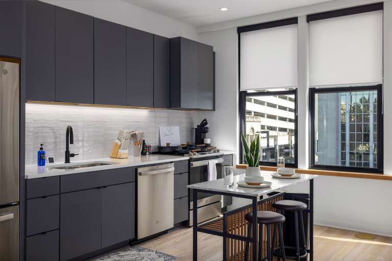 Bright and modern—the kitchen combines sleek cabinetry, high-end appliances, and an elegant dining area bathed in natural light from large windows, offering a perfect spot for meals with a view.