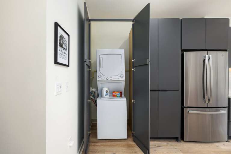 Efficiency meets style—the laundry area is discreetly hidden behind sleek cabinetry, featuring a washer-dryer combo for your convenience.