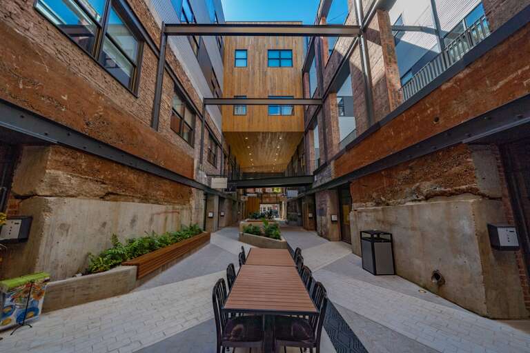 This photo captures a bustling corridor within a renovated industrial complex, where modern elements and historical architecture merge, featuring commercial spaces. This photo captures a bustling corridor within a renovated industrial complex, where modern elements and historical architecture merge, featuring commercial spaces.
