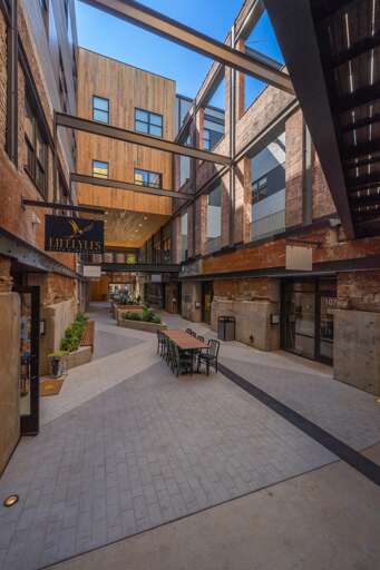 A spacious urban courtyard framed by modern and historical architectural elements, featuring outdoor seating and pedestrian pathways that invite visitors to enjoy the open air setting. A spacious urban courtyard framed by modern and historical architectural elements, featuring outdoor seating and pedestrian pathways that invite visitors to enjoy the open air setting.