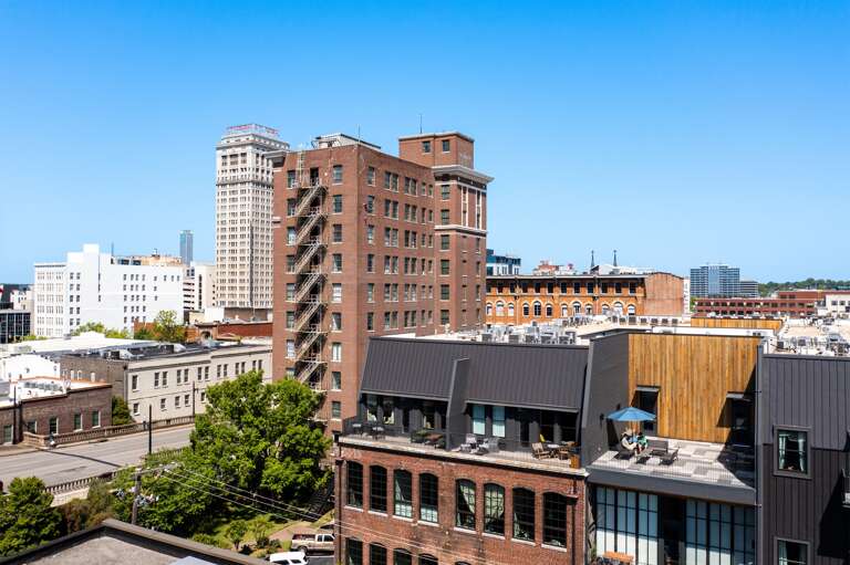 A broad view of Birmingham's downtown area under clear skies, showcasing dense clusters of mid-rise and high-rise buildings. A broad view of Birmingham's downtown area under clear skies, showcasing dense clusters of mid-rise and high-rise buildings.