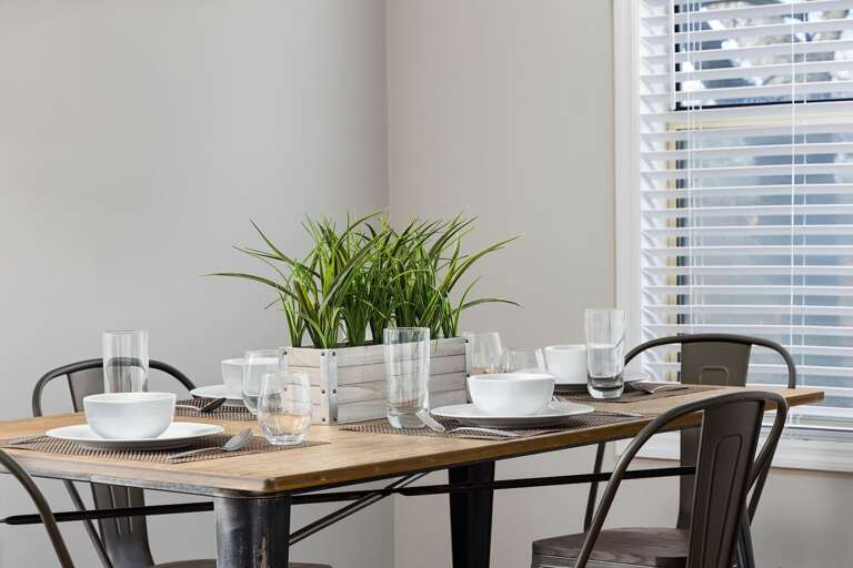 Close-up of the dining table setup with elegant dishware and a centerpiece, ready for guests. Close-up of the dining table setup with elegant dishware and a centerpiece, ready for guests.