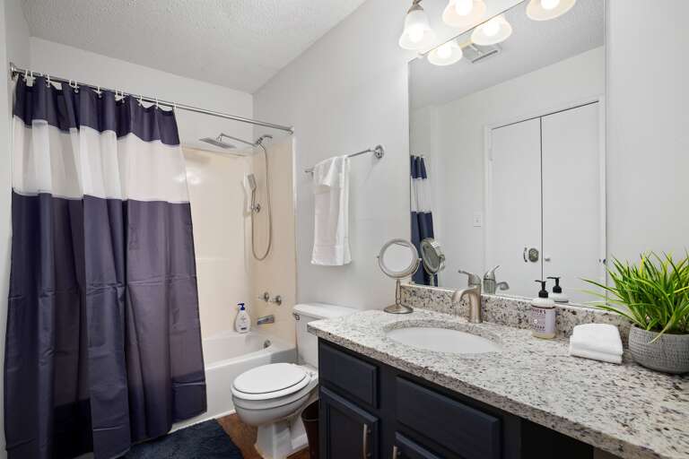 Bathroom with a clean design, featuring a shower/tub combo, double sinks, and fresh towels. Bathroom with a clean design, featuring a shower/tub combo, double sinks, and fresh towels.