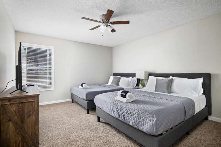 Spacious bedroom with two comfortable queen-size beds, a ceiling fan, and a smart TV. Spacious bedroom with two comfortable queen-size beds, a ceiling fan, and a smart TV.