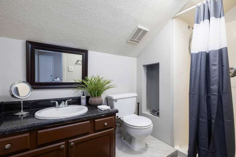 Stylish bathroom with a clean design, featuring a granite countertop and a shower/tub combo.