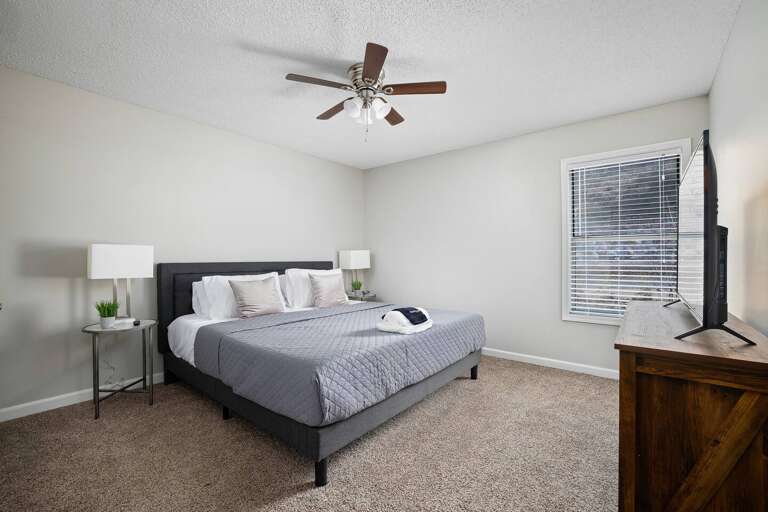 Cozy bedroom with a plush king-size bed, bedside tables, and natural light from large windows.