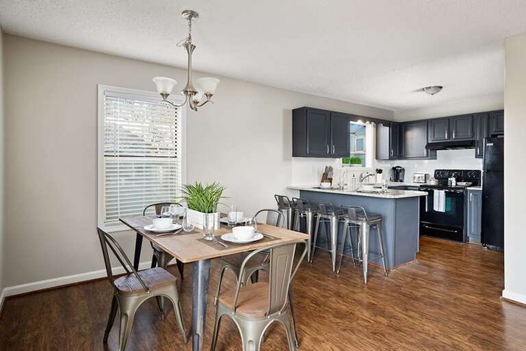 Dining area and kitchen with a modern layout, featuring a table set for meals and sleek bar seating.