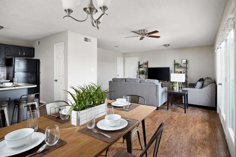 Open-concept dining and living area with a table set for meals and comfortable seating throughout.