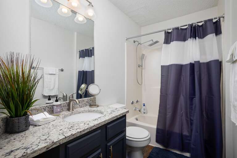 Stylish bathroom with a double vanity, granite countertops, and a shower/tub combo for a modern, clean look.