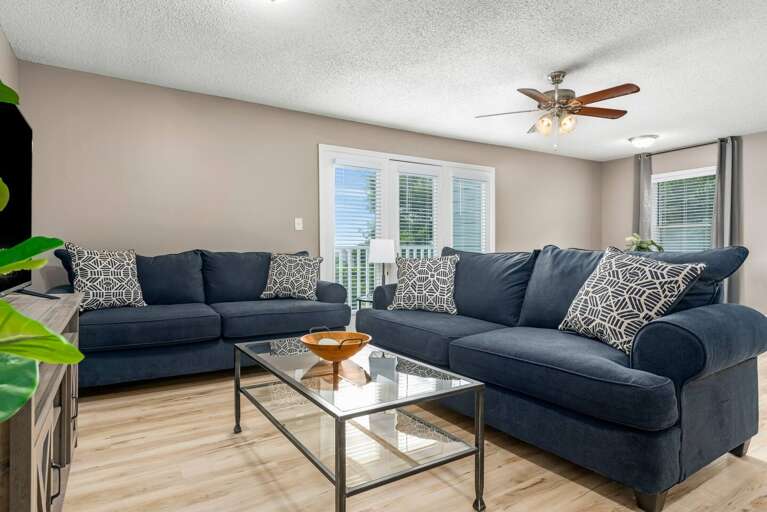 Living room with a plush navy sectional, modern coffee table, and access to natural light.