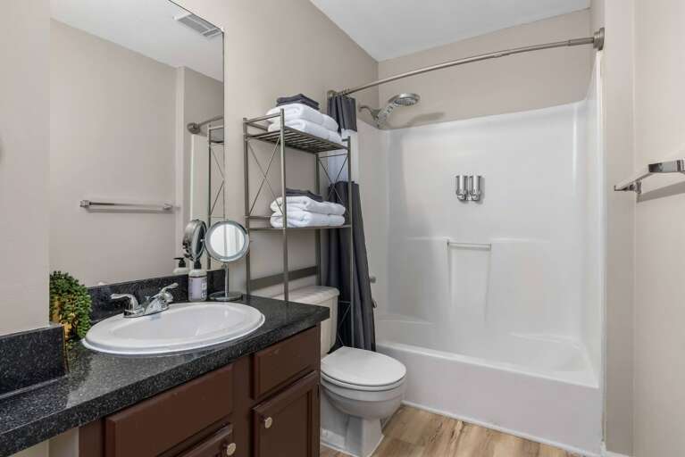 Another bathroom view featuring a modern vanity, shower, and storage space for guests.