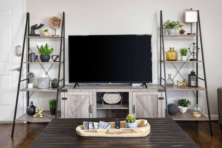 Entertainment center with a large TV and stylish shelves decorated with modern accents.