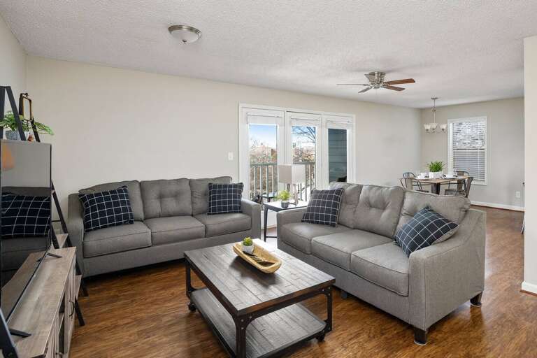 Living room with a gray sectional, coffee table, and open access to the balcony.