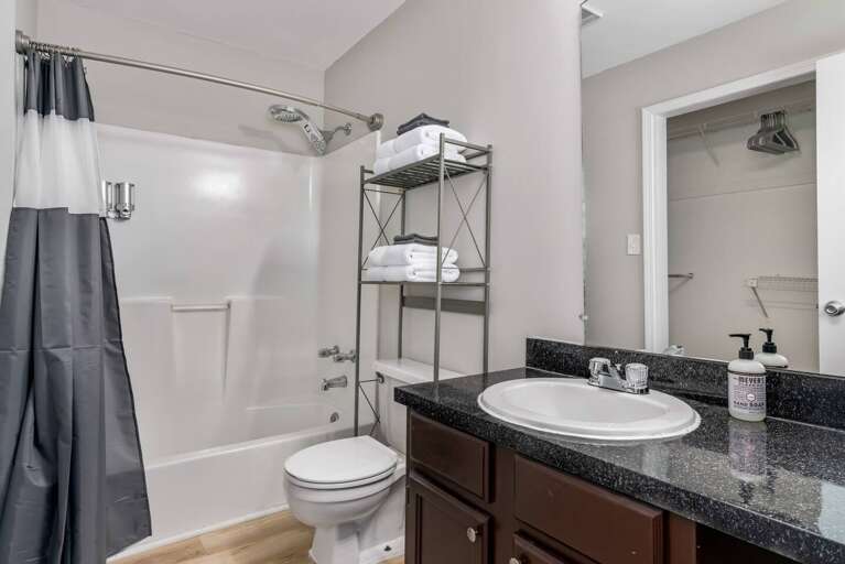 Clean bathroom with a shower/tub combo, towel rack, and a sleek countertop.