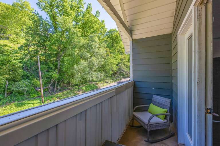 Front balcony with two rocking chairs and serene greenery views, perfect for relaxing.