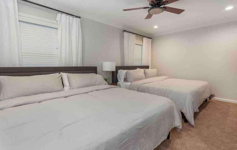 Spacious bedroom with two comfortable beds, soft linens, and a ceiling fan for added comfort. Spacious bedroom with two comfortable beds, soft linens, and a ceiling fan for added comfort.