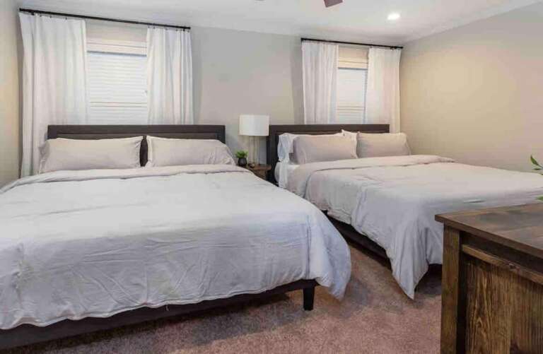 Bright bedroom with twin beds, elegant decor, and plenty of natural light. Bright bedroom with twin beds, elegant decor, and plenty of natural light.