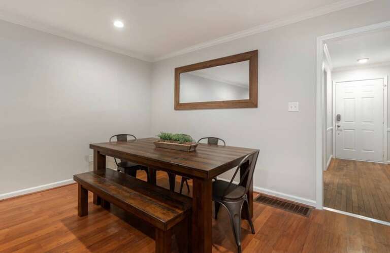 Elegant dining area with a wooden table, seating for six, and a large mirror accent. Elegant dining area with a wooden table, seating for six, and a large mirror accent.