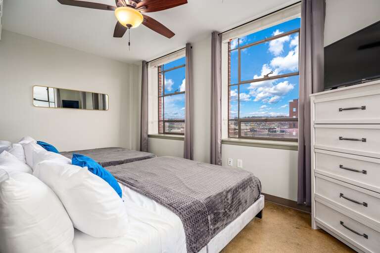 Bright bedroom with two queen beds, modern decor, and large windows offering stunning city views.