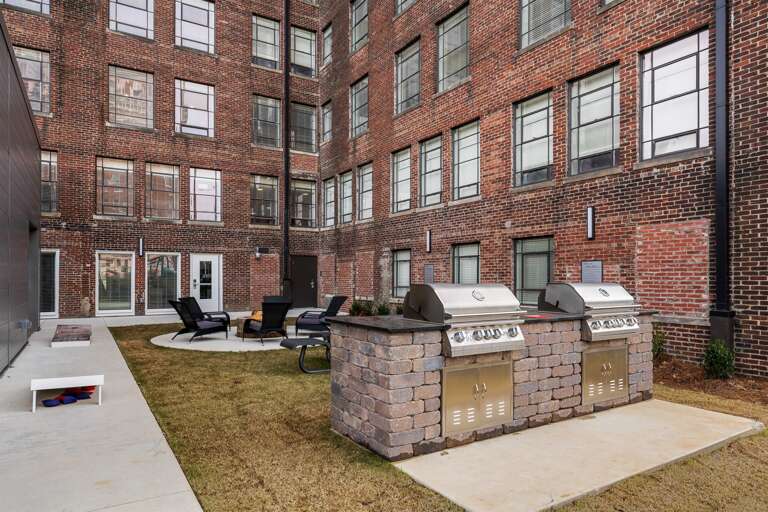 Historic outdoor courtyard with a mix of charm and comfortable seating, featuring two grills for common use.