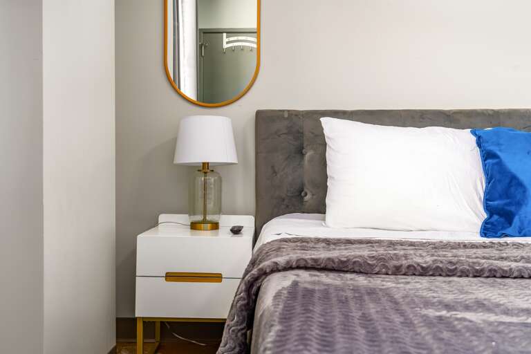 Cozy bedroom with a king-size bed, elegant decor, and natural light from large windows.