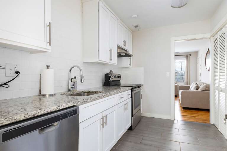A closer look at the granite countertops and well-organized kitchen layout, complete with a dishwasher and ample cabinet storage.