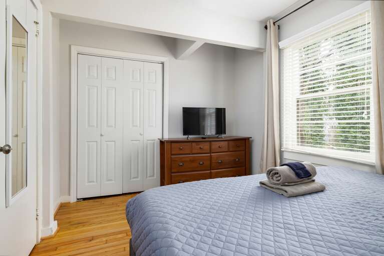 The master bedroom also includes a spacious dresser, a smart TV, and closet space for a comfortable and organized stay.