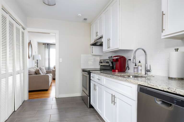 Another angle of the kitchen highlighting the sleek layout and open access to the dining and living areas.