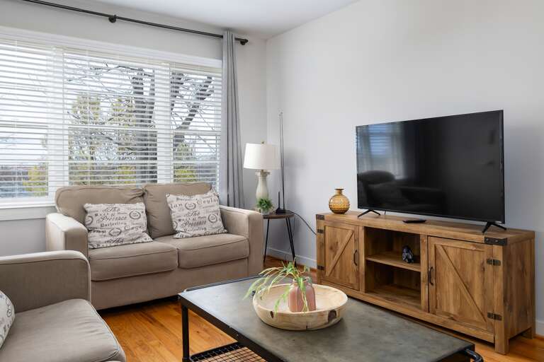 A closer view of the living room setup, including a smart TV and neutral-toned couches for a relaxing and cohesive design.