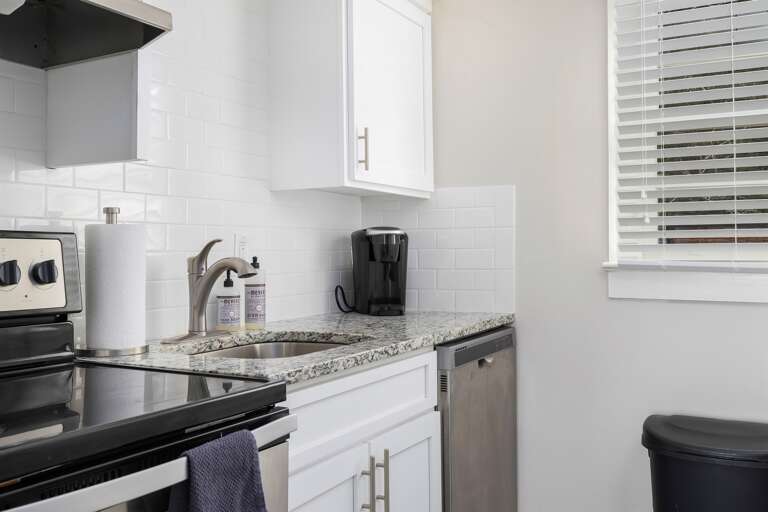 Fully equipped kitchen featuring stainless steel appliances, granite countertops, and white cabinetry. Perfect for cooking meals or enjoying a morning coffee.