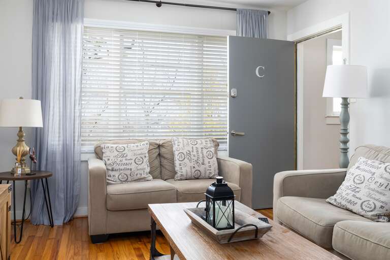 Bright and spacious living room in Unit C, featuring cozy seating, a smart TV, and soft curtains for added comfort. Bright and spacious living room in Unit C, featuring cozy seating, a smart TV, and soft curtains for added comfort.