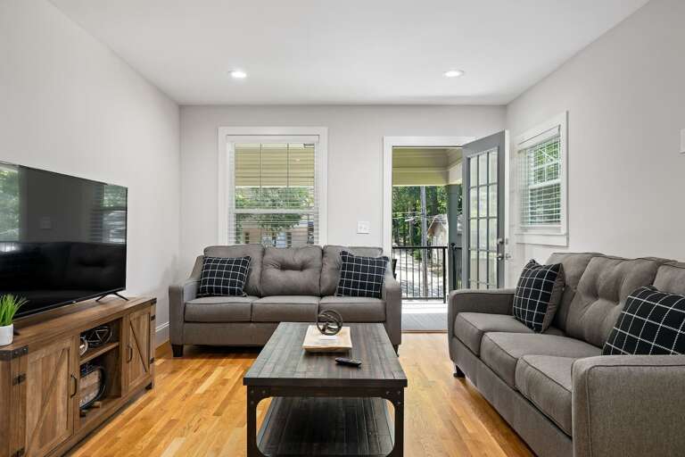 Detailing the living area's cozy furnishings and stylish decor, perfect for relaxing evenings or entertaining guests. The door leads directly to the balcony.