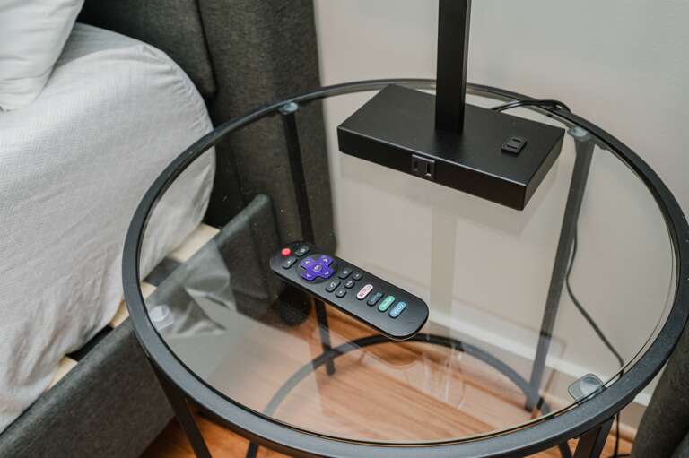A convenient round table featuring a stylish lamp and remote, perfect for leisurely reads or cozy evenings.