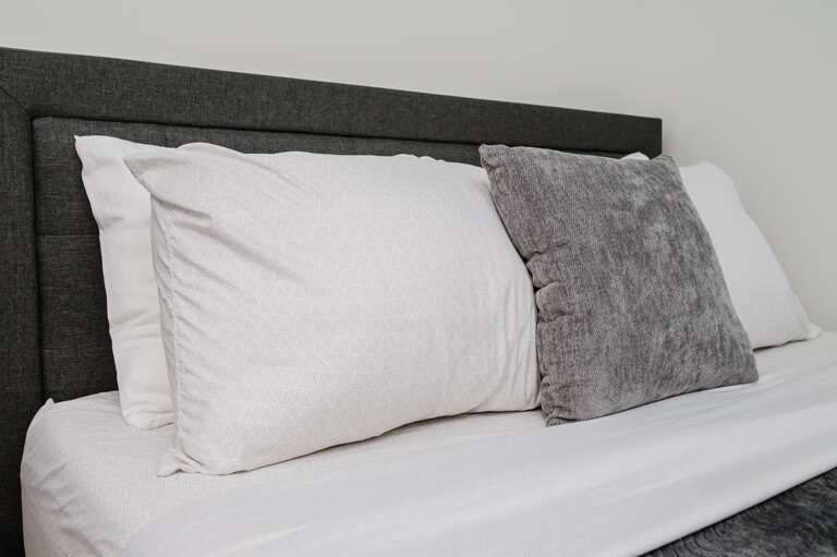 A relaxing nook featuring a comfortable bed with plush pillows and a chic side table.