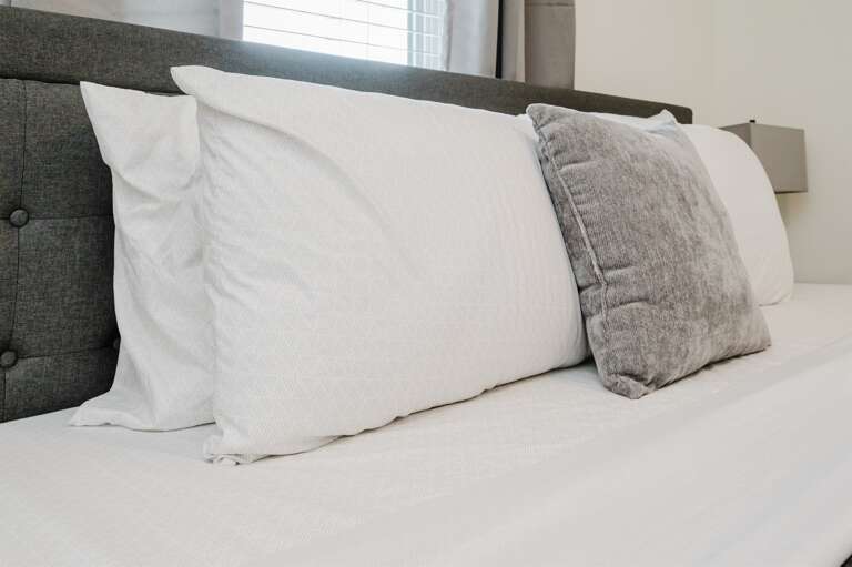 Focus on comfort with plush pillows against a stylish headboard in a serene bedroom setting.