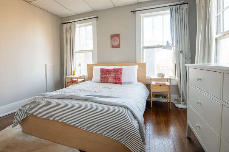 Bright bedroom with a comfortable bed and a view of the neighborhood.