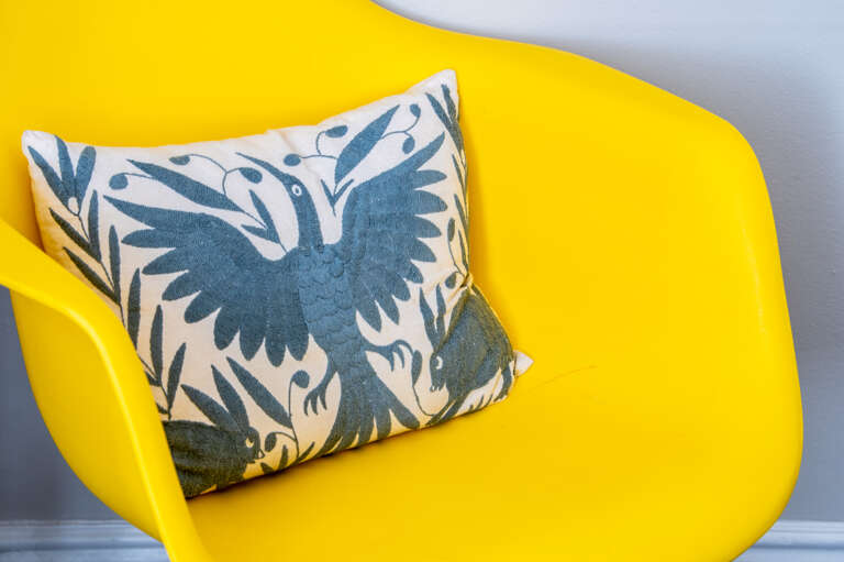 Bright and cheerful yellow chair with a decorative blue and white pillow for a cozy touch in the double full bedroom Bright and cheerful yellow chair with a decorative blue and white pillow for a cozy touch in the double full bedroom