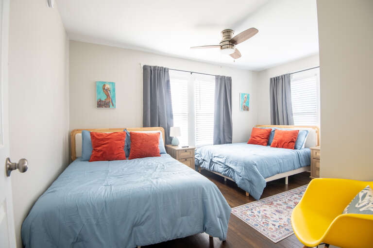 Bright and airy bedroom featuring two comfortable full beds with stylish blue and orange decor Bright and airy bedroom featuring two comfortable full beds with stylish blue and orange decor
