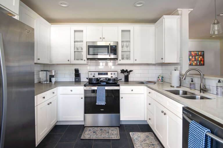 Fully equipped modern kitchen with stainless steel appliances, white cabinets, and great lighting.