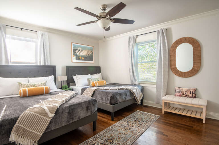 Spacious double queen room with two beds, ceiling fan, and cozy touches—ideal for kids or extra guests.