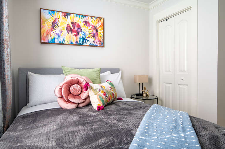 Colorful florals add charm to this queen bedroom, complete with fresh linens and a restful vibe.