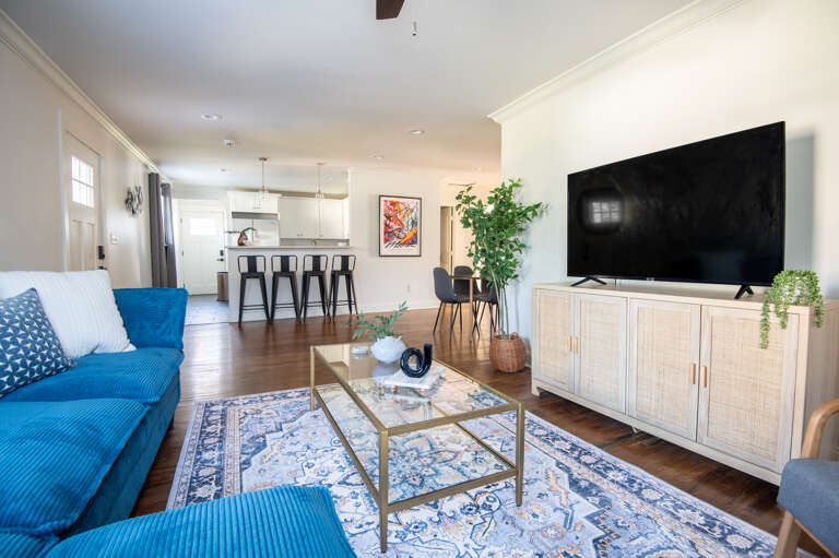 Bright, open-concept living space with comfy seating, bar stools, and a view into the kitchen.