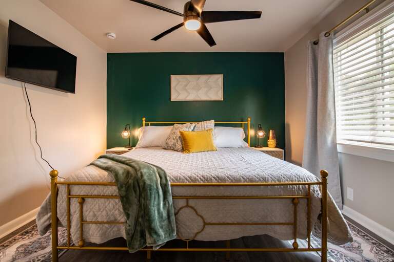Elegant bedroom featuring a comfortable king bed set against a striking green accent wall.