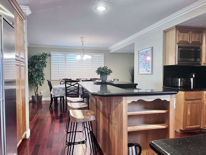 Spacious Kitchen With A Dining Area, Polished Wooden Cabinets, And Glossy Floors Spacious Kitchen With A Dining Area, Polished Wooden Cabinets, And Glossy Floors