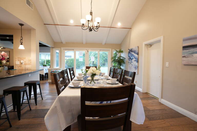 Spacious Dining Setting With Sleek Chairs, Polished Table, Pendant Lighting