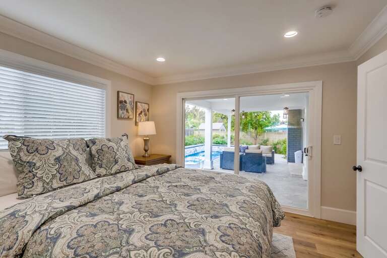 Polished Bedroom With Patterned Bedding, Leading To A Pool