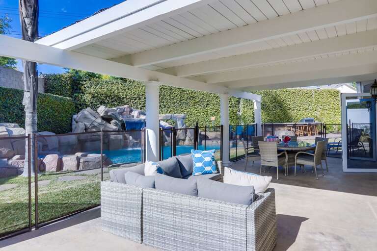 Outdoor seating, dining and view of fence in pool
