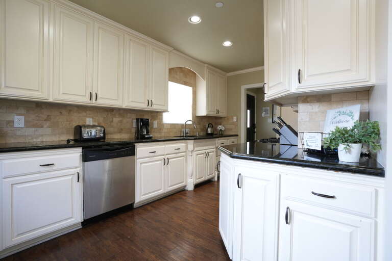 Spacious Kitchen With White Cabinets And Brown Backsplash
