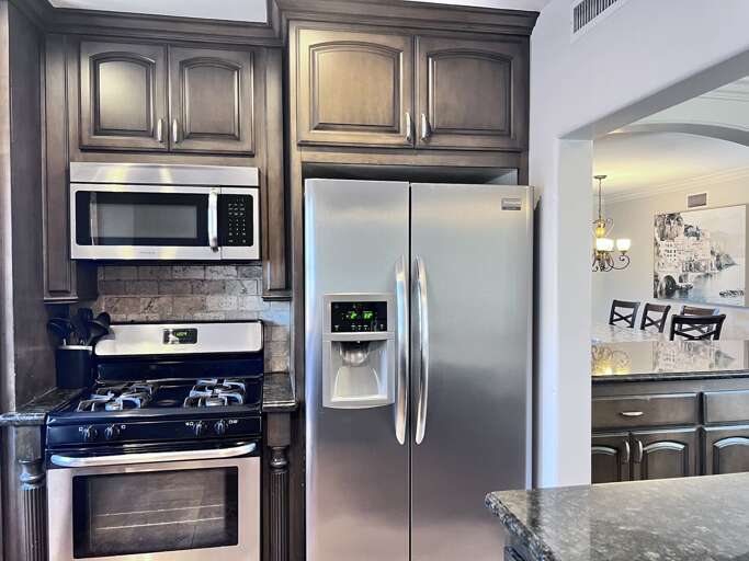Kitchen With Stainless Steel Appliances And Dark Wooden Cabinets Kitchen With Stainless Steel Appliances And Dark Wooden Cabinets